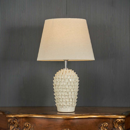 Ceramic table lamp illuminated on a dark background highlighting the warm glow and detailed blue pattern in a dramatic premium style.