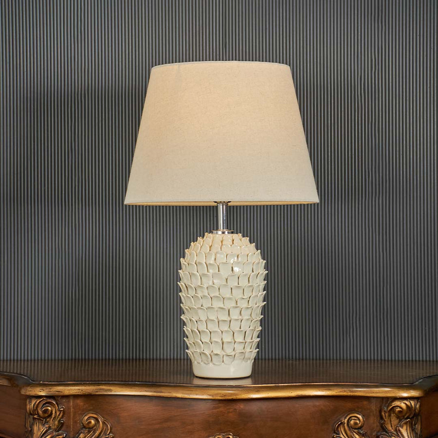 Ceramic table lamp illuminated on a dark background highlighting the warm glow and detailed blue pattern in a dramatic premium style.