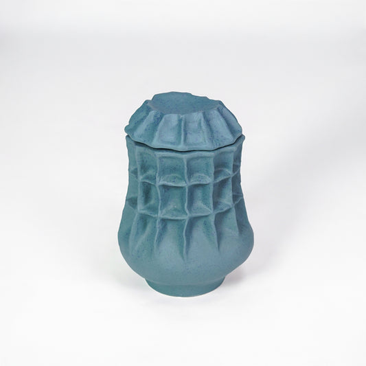 White background image of blue ceramic textured jar for modern tabletop decor styling with artistic matte finish.