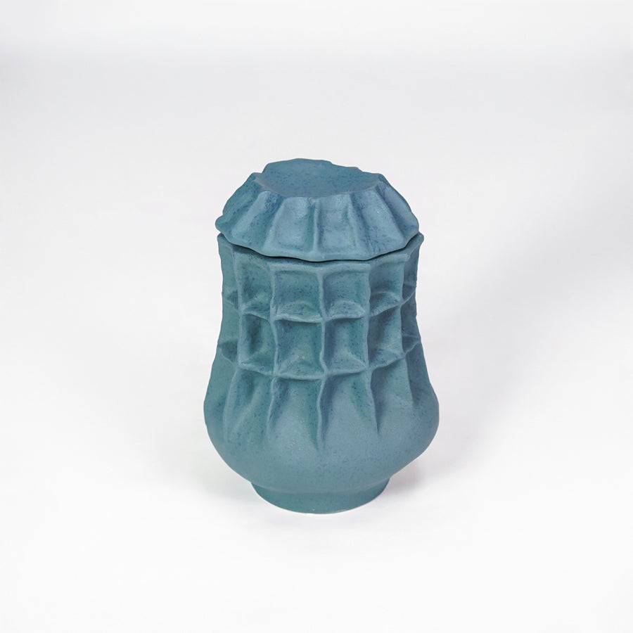 White background image of blue ceramic textured jar for modern tabletop decor styling with artistic matte finish.