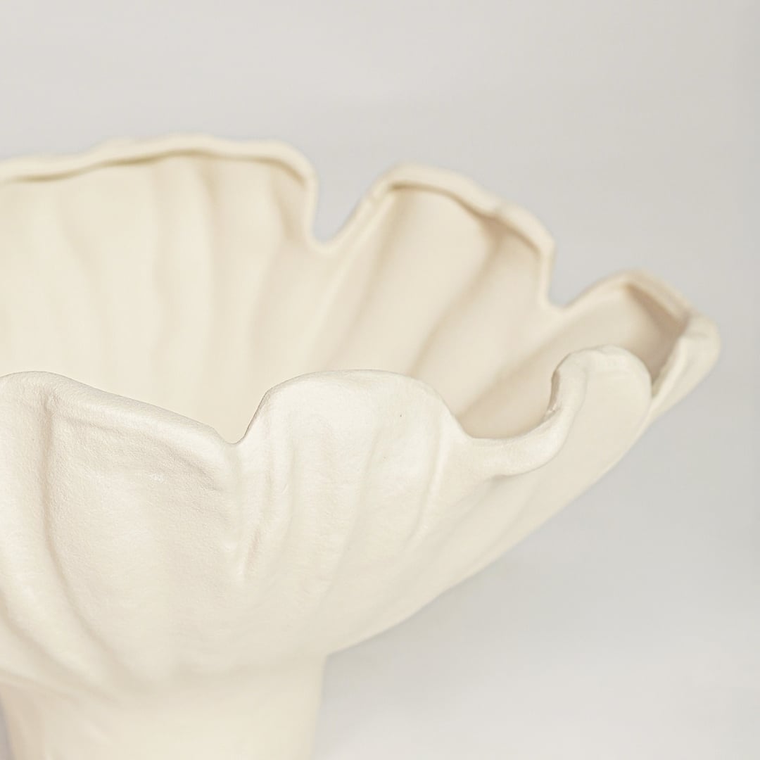 Close view of white ceramic floral bowl featuring soft curved petals and elegant matte finish.