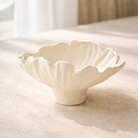 White ceramic floral decorative bowl styled on coffee table enhancing soft and elegant home decor setting.