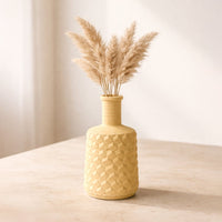 Lifestyle yellow ceramic textured flower vase with dried pampas grass placed on table minimal home decor styling aesthetic interior setup.