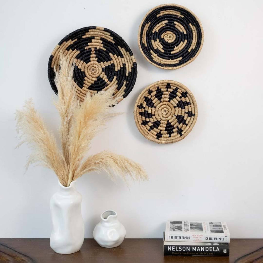 Handwoven seagrass wall basket decor set in natural beige and black creating elegant boho wall decor for home interiors.