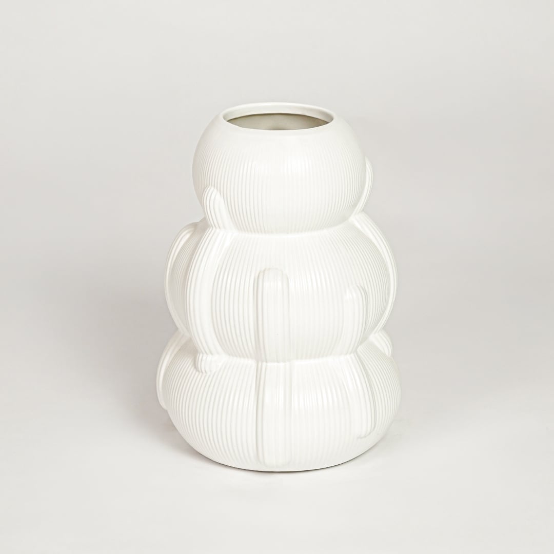 Closeup of glossy white ceramic vase with curved layered form ideal for elegant home decor shelf or side table styling.