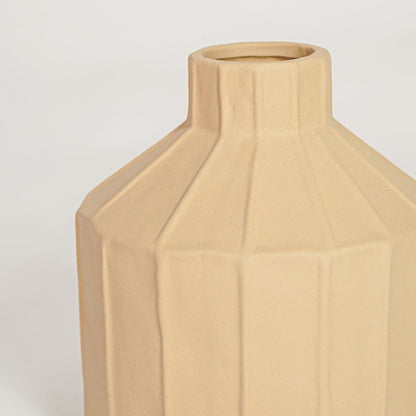 Closeup of matte beige ceramic vase with angular sculpted texture ideal for elegant home decor shelf styling.