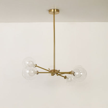 Gold metal chandelier with clear glass globe shades and branching frame designed for stylish modern ceiling lighting.