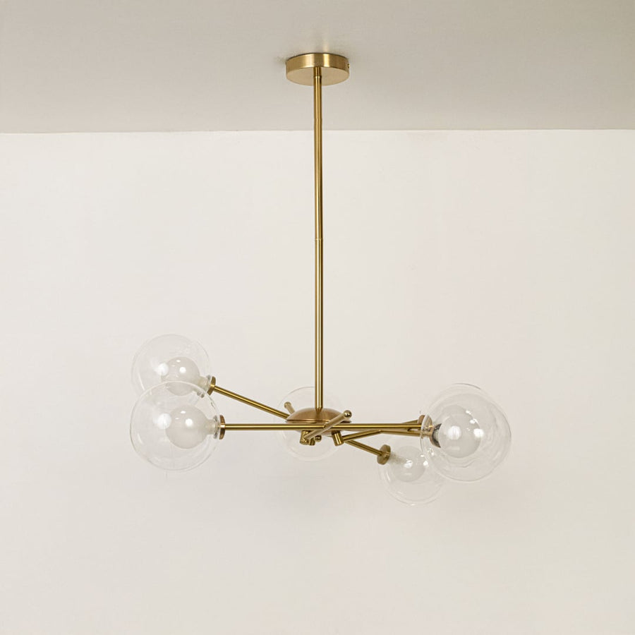 Gold metal chandelier with clear glass globe shades and branching frame designed for stylish modern ceiling lighting.
