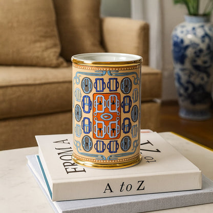 Decorative ceramic jar with colorful pattern placed on stacked books beside sofa enhancing contemporary living room decor styling.