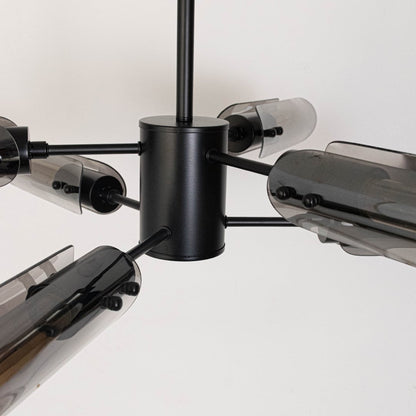Closeup of black metal chandelier showing smoky glass tube lights with warm glow for luxury contemporary ceiling decor.