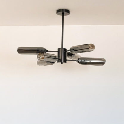 Black metal chandelier with smoky grey glass tubes displayed off on white background showcasing sleek modern lighting design.