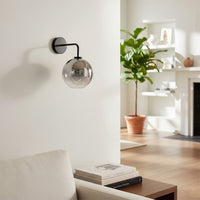 Modern black wall light with smoked glass globe creating cozy contemporary bedroom lighting ambiance.