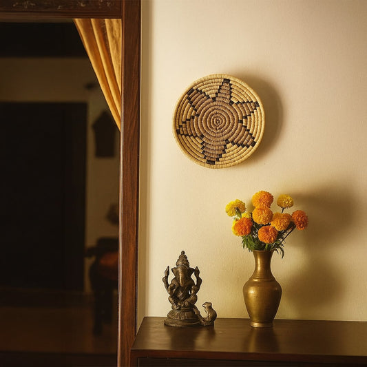 Handwoven round wall basket Decor styled on a warm beige wall above a wooden console with brass vase marigold flowers and a traditional accent creating a cozy ethnic interior scene.