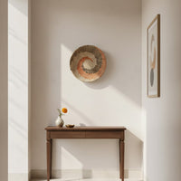Decorative round wall art in natural fiber finish mounted above wooden console table adding warm texture and modern home decor style.