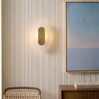 Modern oval frosted glass wall sconce with gold brass accent on striped wallpaper for elegant living room home decor.