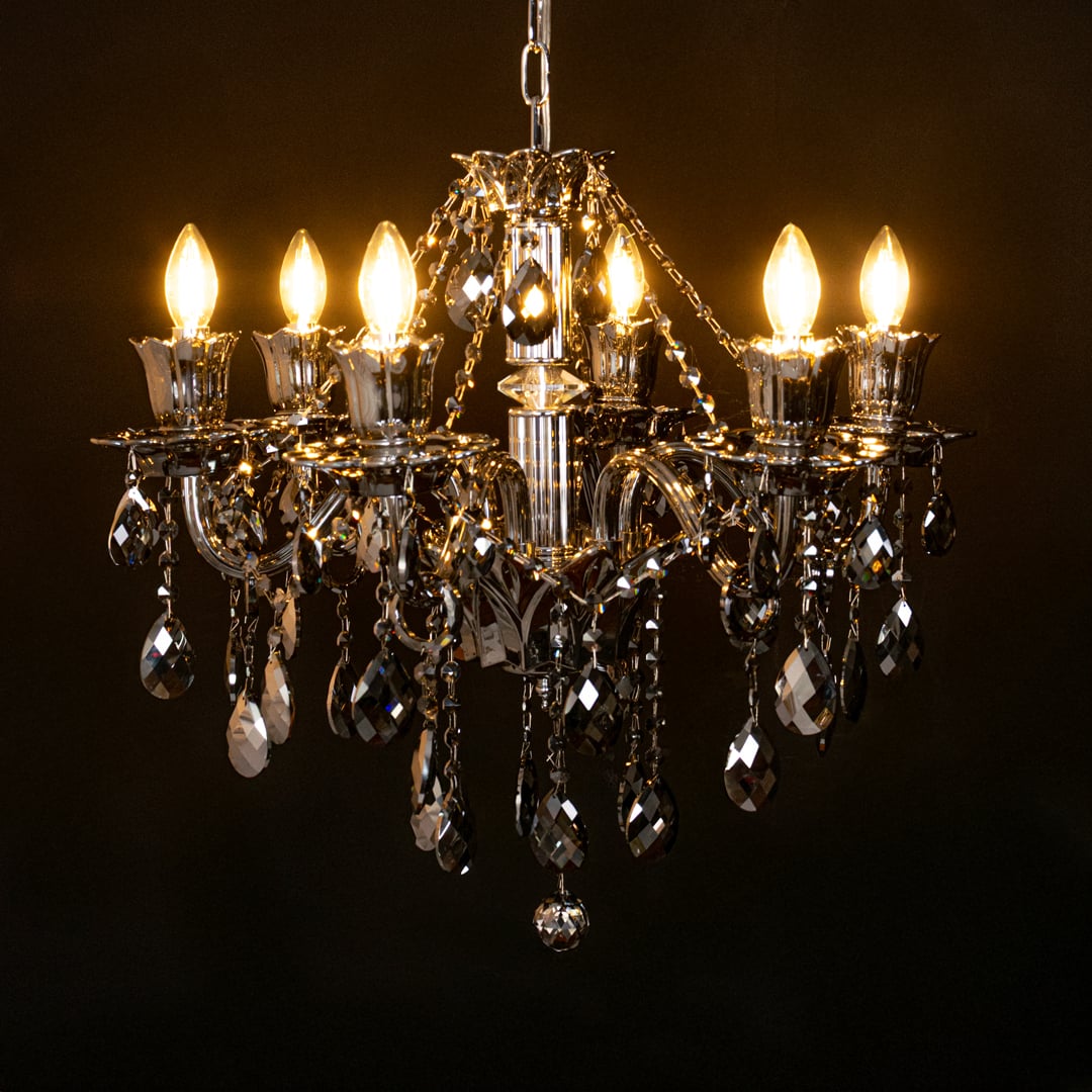 Black crystal chandelier glowing warmly on black background creating a dramatic luxury ceiling statement.