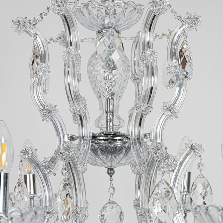 Closeup of chrome crystal chandelier arms and hanging drops showing detailed glass craftsmanship for premium home lighting.