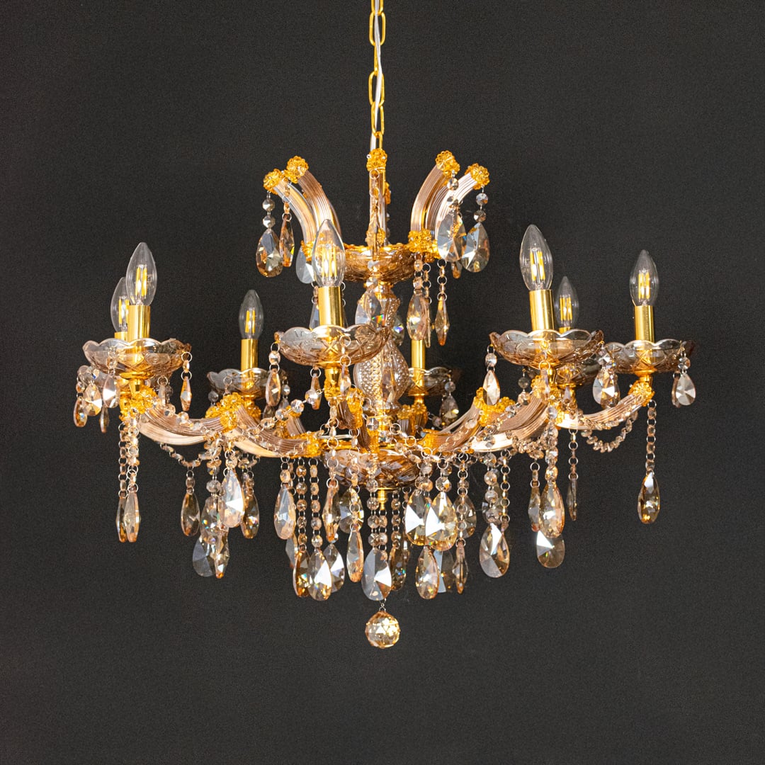 Gold crystal chandelier with detailed glass drops displayed on black background for a dramatic luxury decor style.