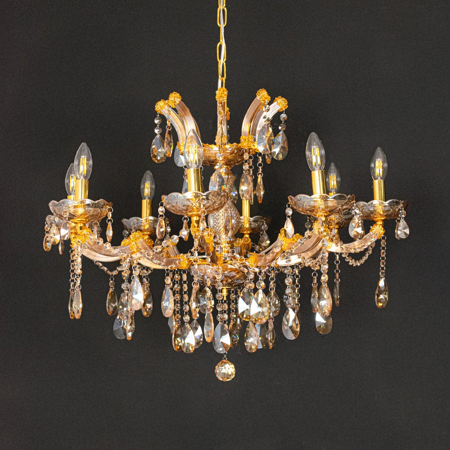 Gold crystal chandelier with detailed glass drops displayed on black background for a dramatic luxury decor style.