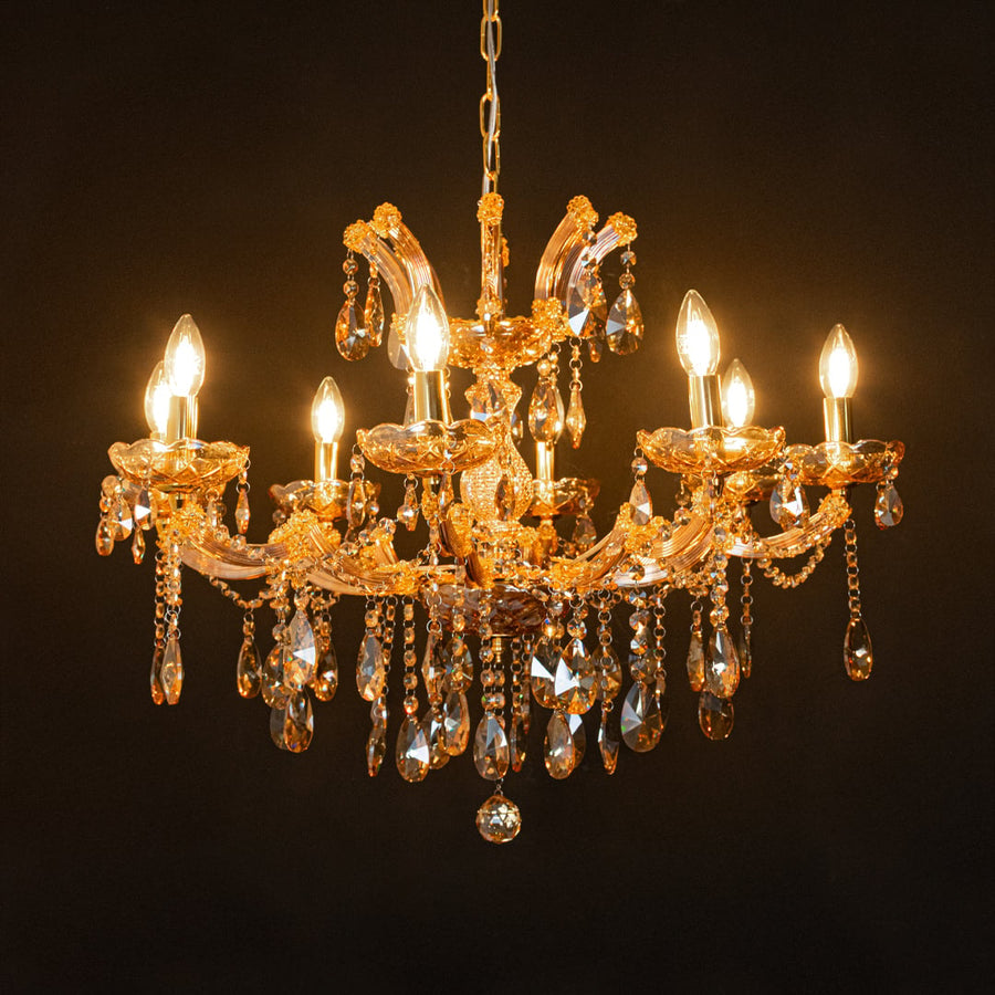 Gold crystal chandelier glowing against black background highlighting warm light and luxury interior style.