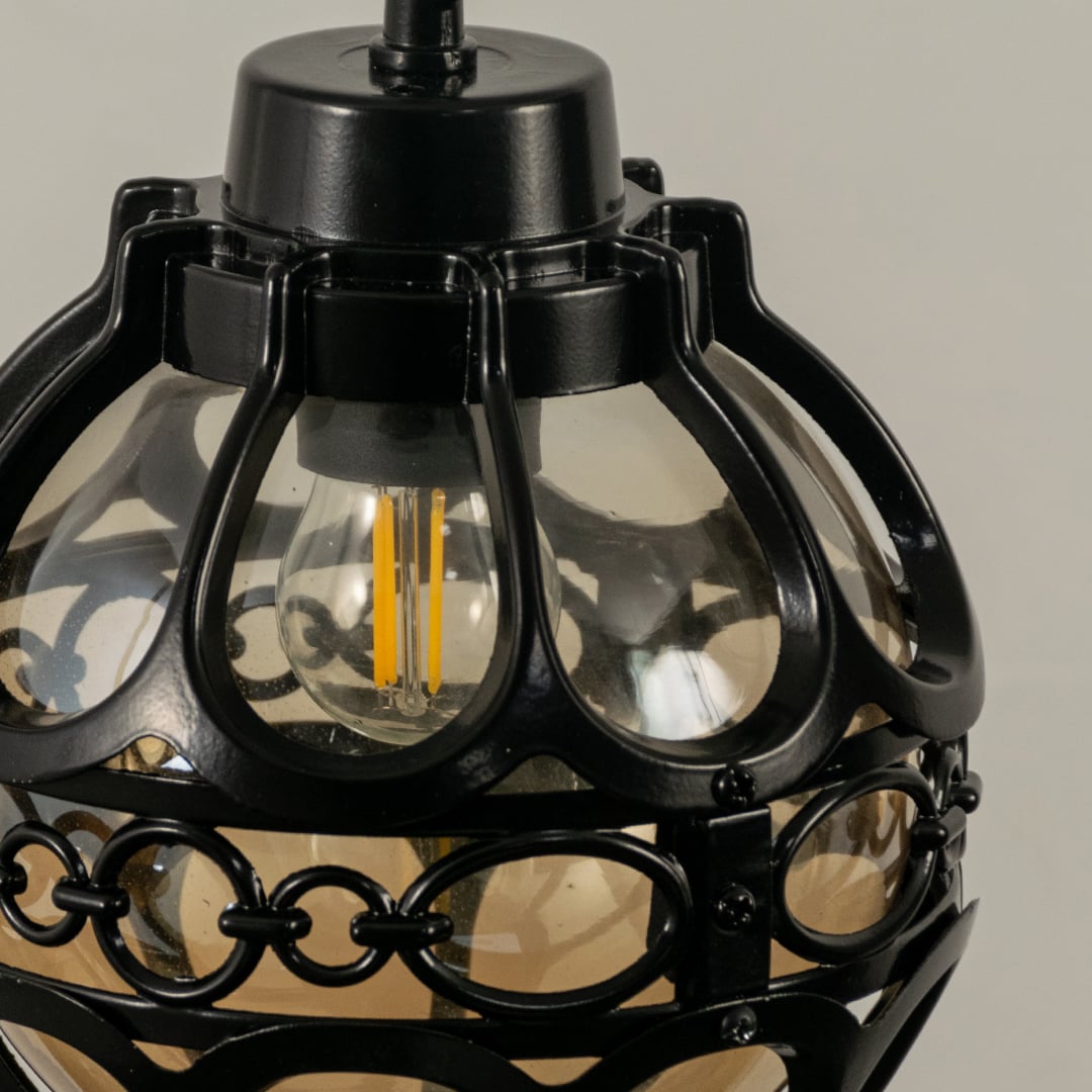 Close up view of the decorative metal rings and inner glass globe of the black spherical cage pendant light fixture.