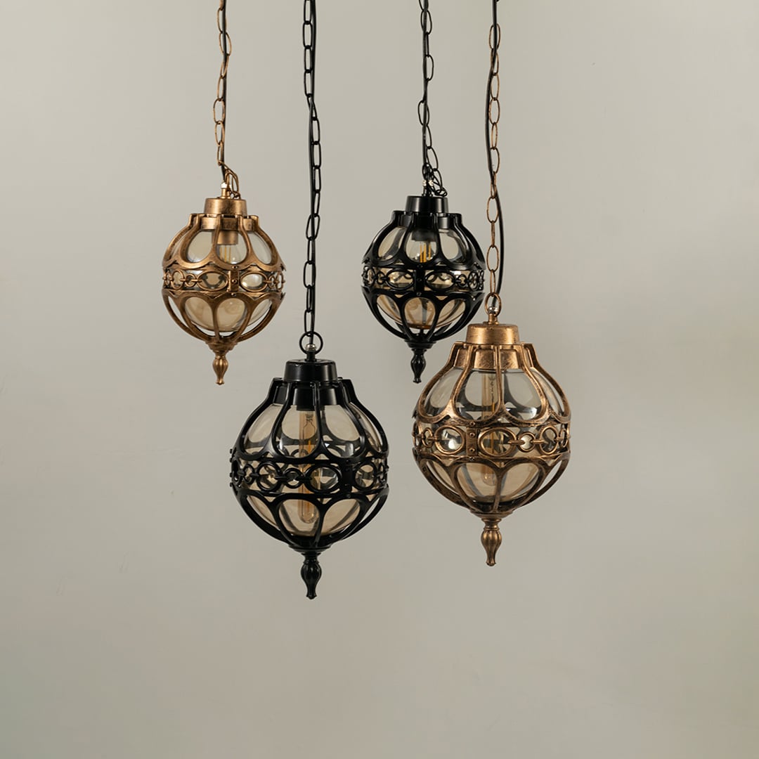 Collection of spherical outdoor hanging lamps in black and antique brass finishes suspended together with lights off.