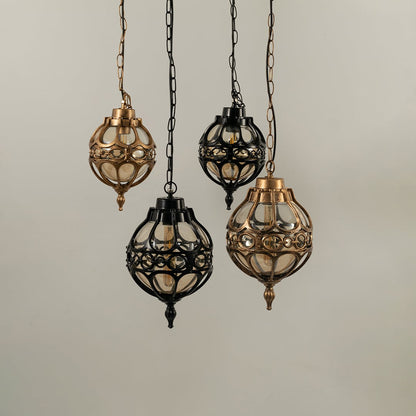 Collection of spherical outdoor hanging lamps in black and antique brass finishes suspended together with lights off.