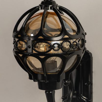Closeup of black metal outdoor wall lantern with detailed globe frame showing textured glass panels for elegant classic exterior lighting.
