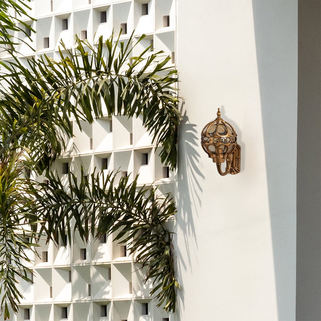 Gold metal outdoor wall lantern mounted on a modern exterior wall adding stylish decorative lighting to enhance outdoor architectural design.