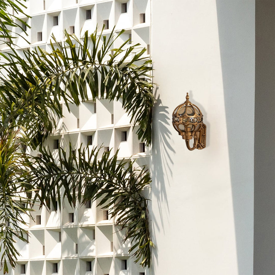 Gold metal outdoor wall lantern mounted on a modern exterior wall adding stylish decorative lighting to enhance outdoor architectural design.