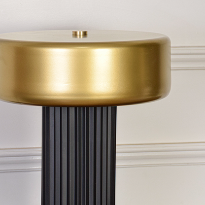 Table lamp closeup highlighting smooth gold shade surface and detailed ribbed black base craftsmanship with soft glow for contemporary home decor.