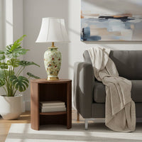 Green ceramic table lamp with hand painted bird floral artwork gold metal base and white fabric shade styled in living room.