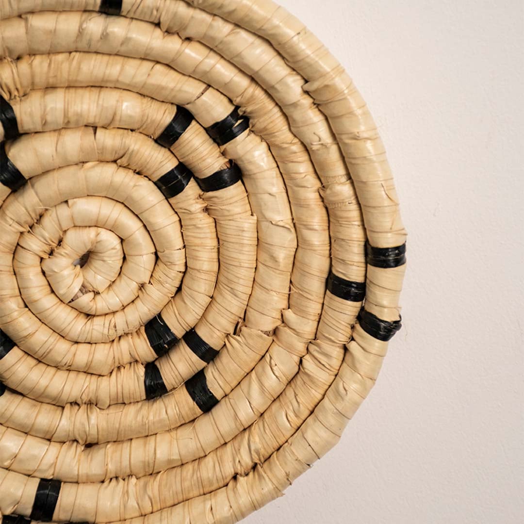 Detailed closeup view of the tight coil weaving and black stitched accents on the natural seagrass wall basket surface quality.