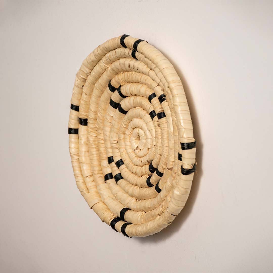 Side view of handcrafted natural cream seagrass wall basket with black stitched cross accents for boho wall decor display.