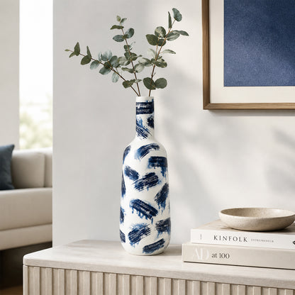 White and blue ceramic flower vase with eucalyptus stems placed on console table for modern home decor.