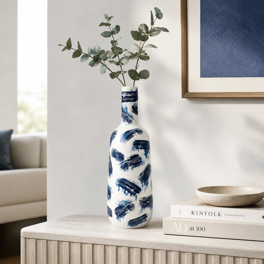 White and blue ceramic flower vase with eucalyptus stems placed on console table for modern home decor.