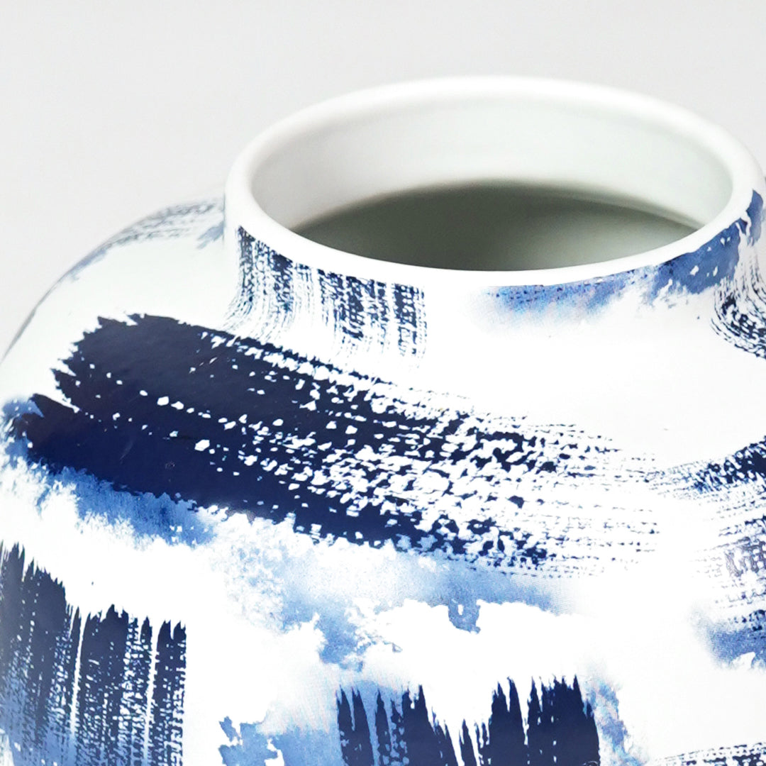 Close-up of artistic blue brushstroke details on white ceramic rounded vase for sophisticated modern interior decor.