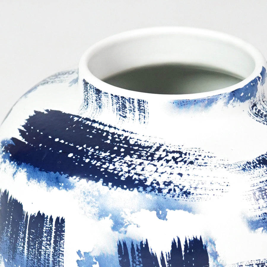Close-up of artistic blue brushstroke details on white ceramic rounded vase for sophisticated modern interior decor.