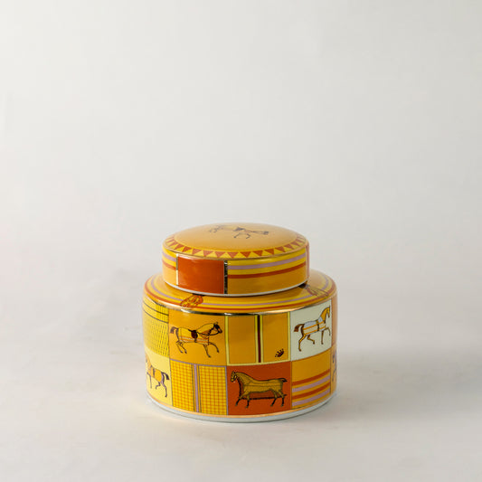 Amber ceramic decorative storage jar with vintage artwork and gold lid for modern tabletop styling and home decor.