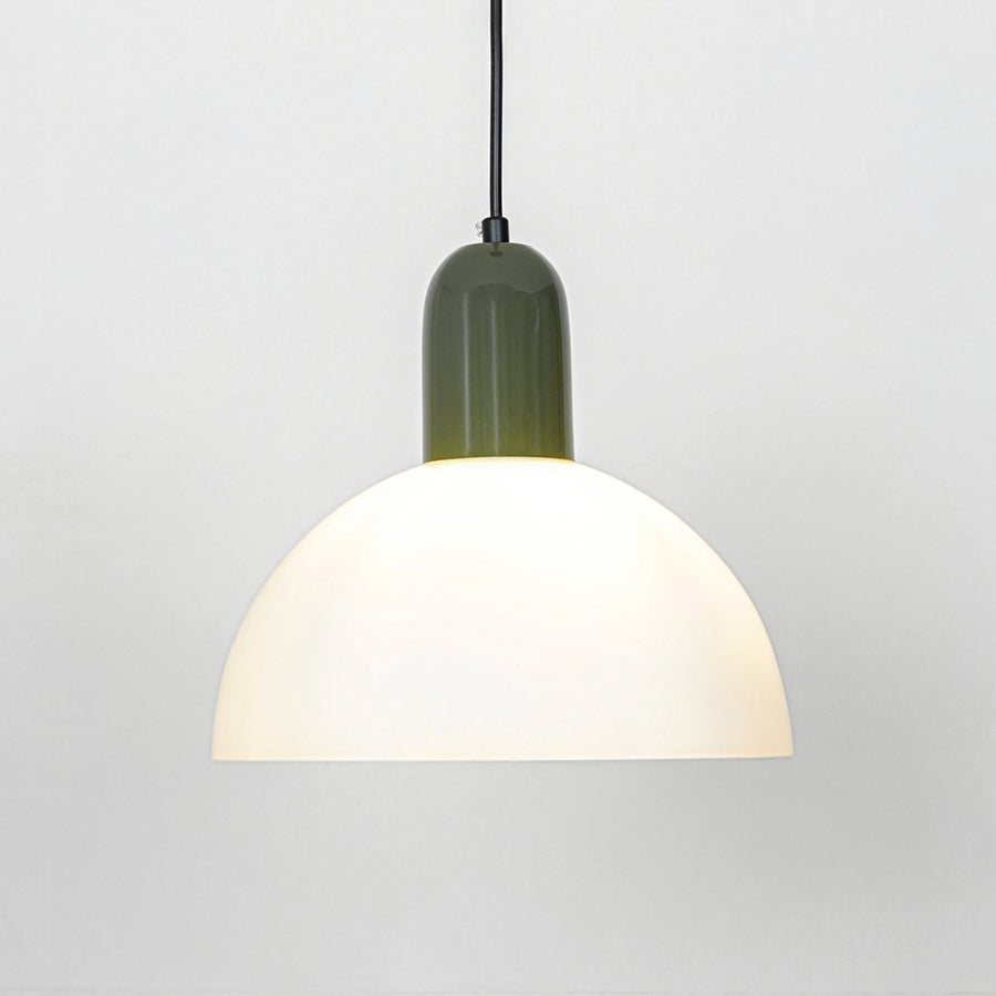 Pendant light with white dome shade and green metal top emitting soft warm glow ideal for kitchen or dining decor placement.