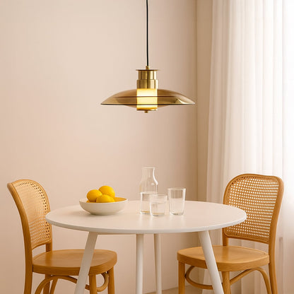 Gold metal disc pendant light adding warm elegance above the dining table in contemporary interiors.