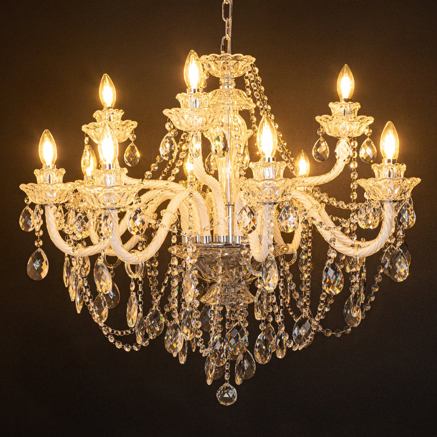 Large clear crystal chandelier glowing warmly on black background creating a dramatic luxury ceiling feature.
