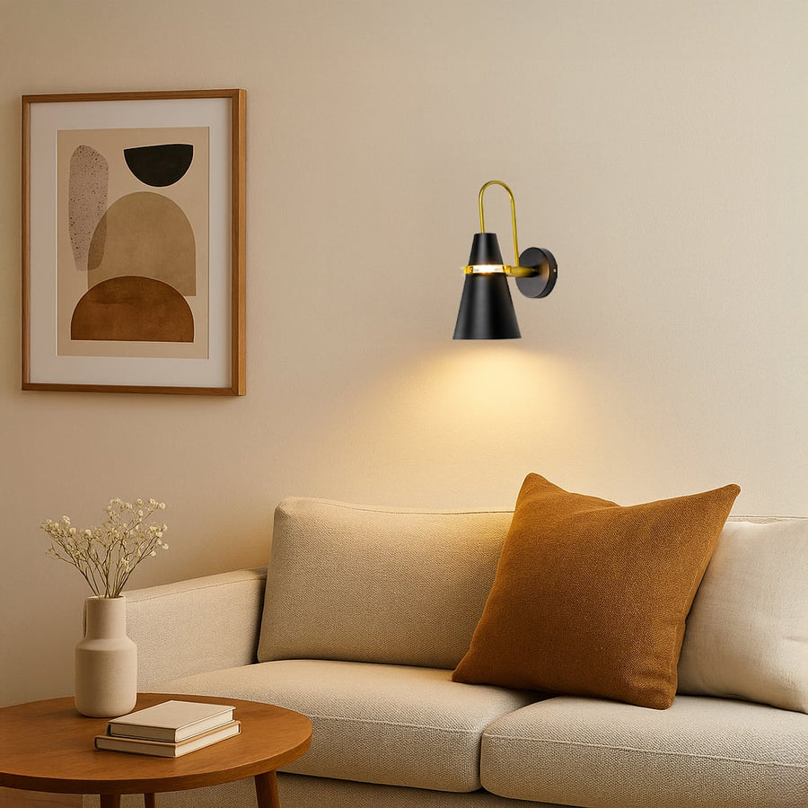 Black and gold wall sconce glowing warmly beside bed adding a touch of luxury and modern style to home interiors.