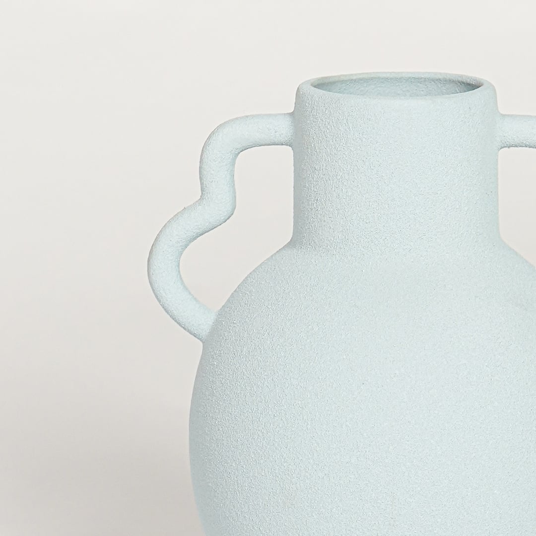 Closeup of slab blue glazed ceramic vase with curved handles showcasing smooth finish for elegant home decor styling.