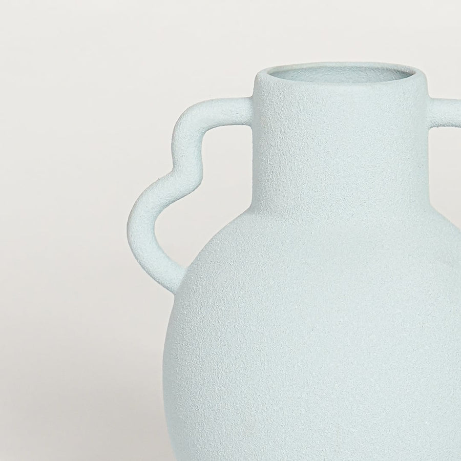 Closeup of slab blue glazed ceramic vase with curved handles showcasing smooth finish for elegant home decor styling.