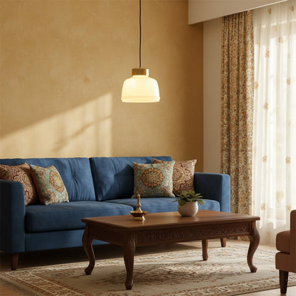 Frosted glass pendant light glowing warmly above a blue sofa and wooden coffee table in a cozy living room.