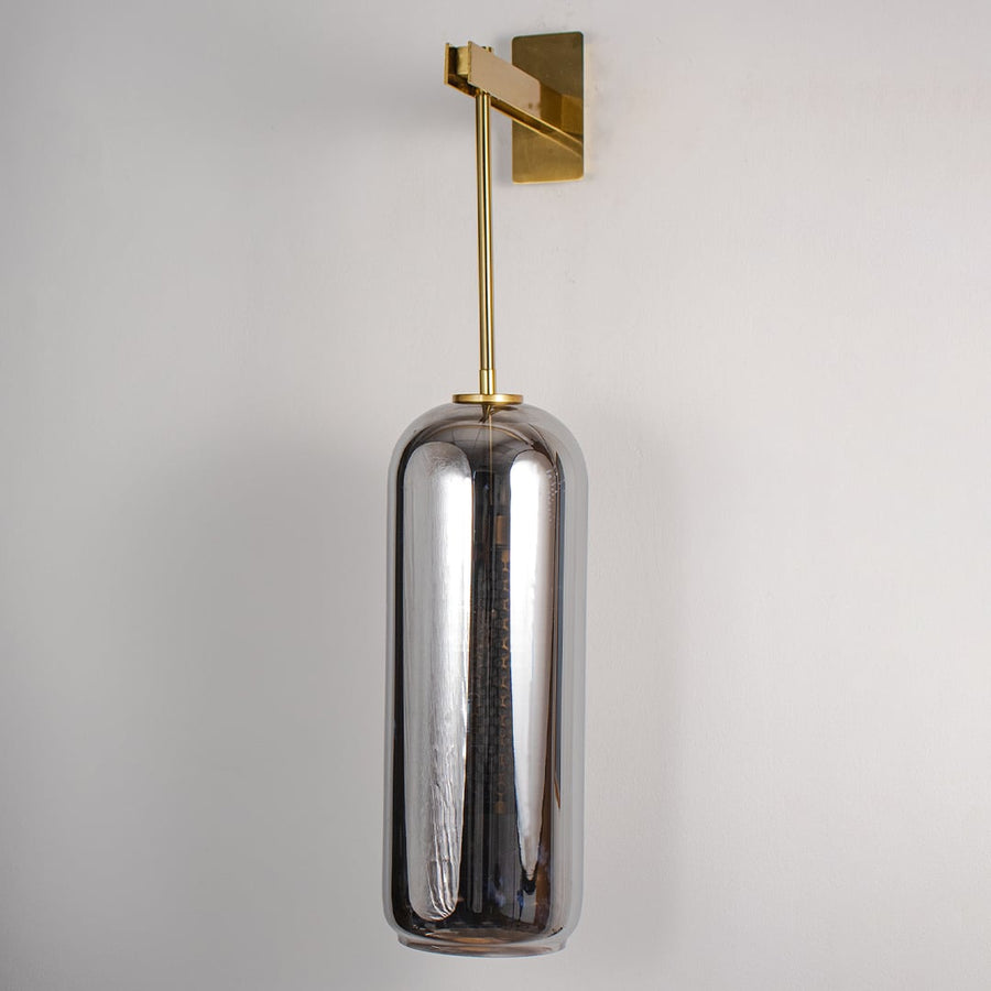Unlit modern wall sconce featuring sleek gold rod and dark glass cylinder isolated on white background for minimalist home styling.