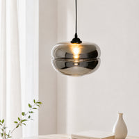 Modern black cord hanging dimpled smoke glass bowl pendant light fixture casting a warm glow in a minimalist room setting.