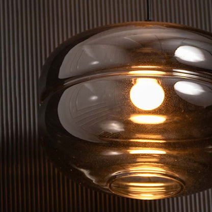 Closeup of smoked glass pendant light capturing its reflective surface warm bulb glow and smooth rounded layered design.