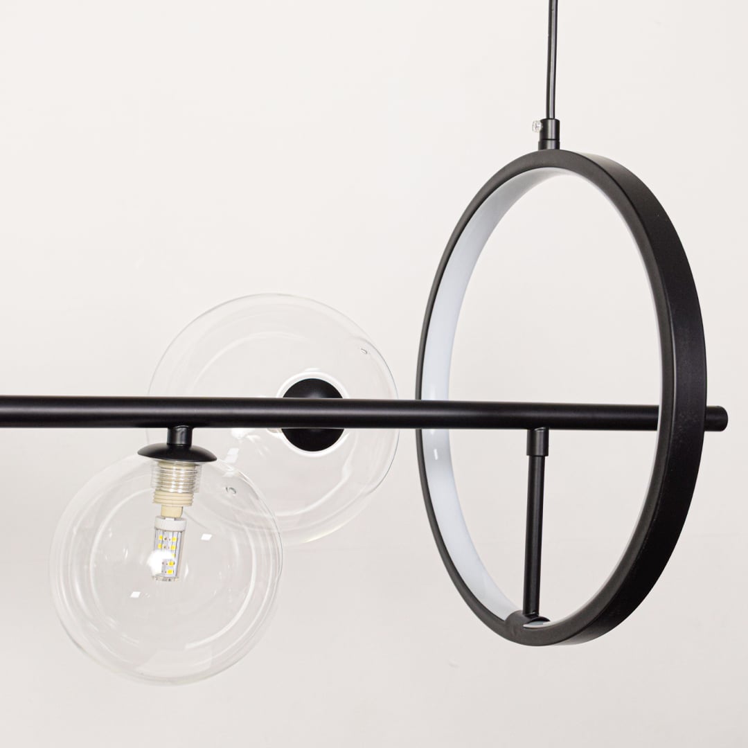 Closeup of modern wall light with black frame clear glass globe and exposed bulb showcasing minimal industrial lighting style.